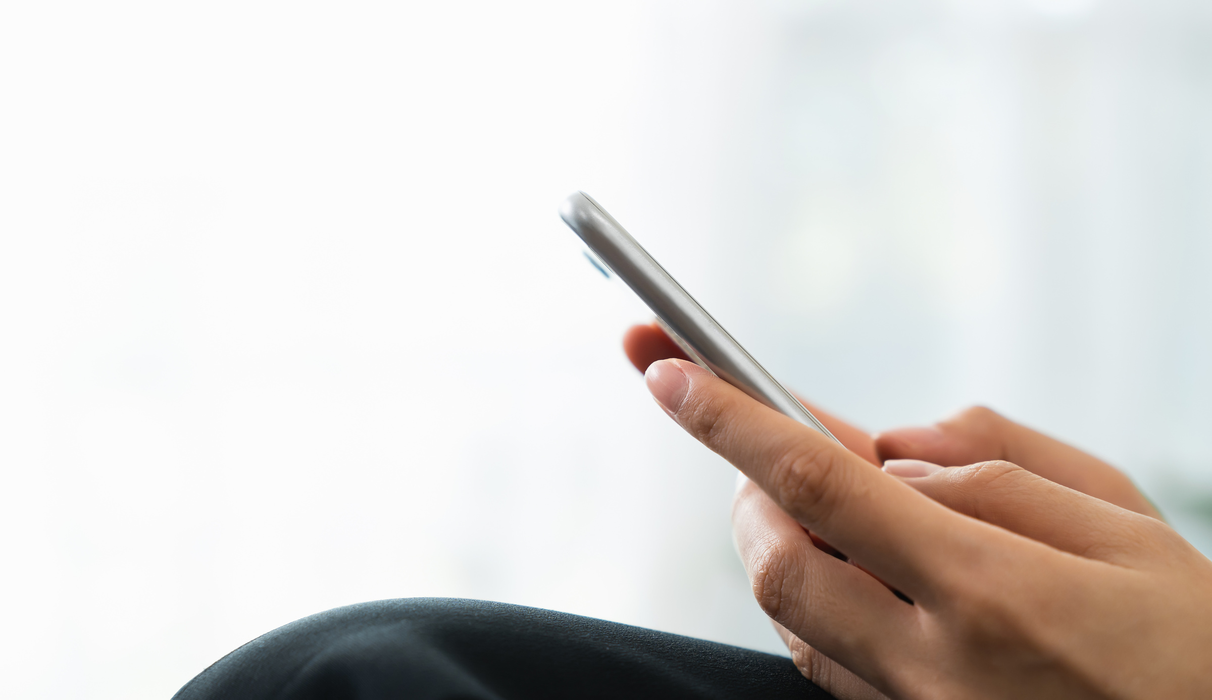 Hand holding smartphone with using social media on internet on sofa in living room.